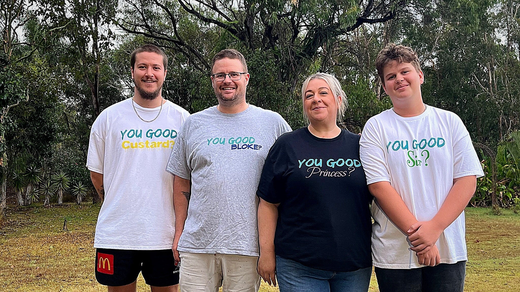 Four people standing outdoors wearing 'You Good' branded shirts.